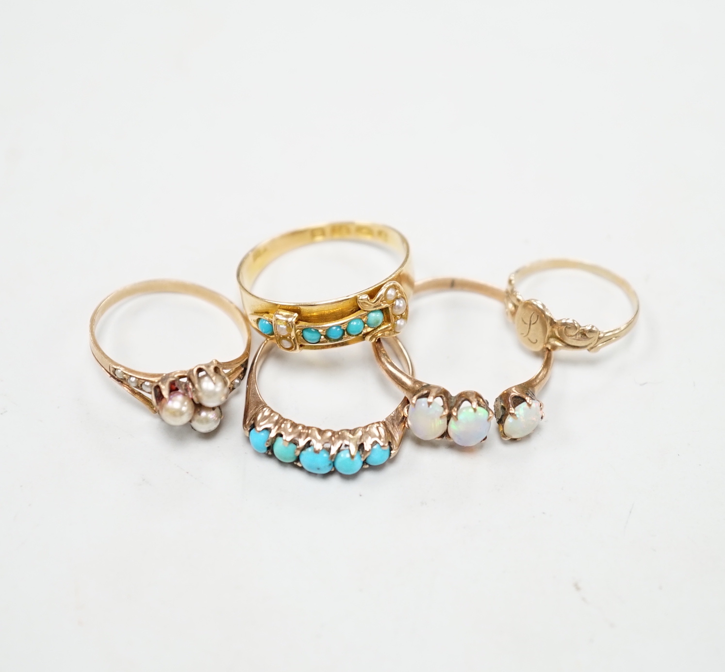 A late Victorian 18ct gold, turquoise and seed pearl set buckle ring, size P and four other yellow metal rings including gem set, gross weight 9 grams (a.f.).